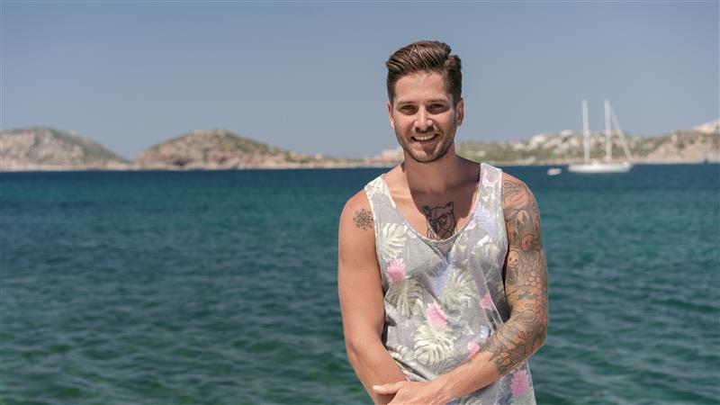 a man in a vest standing by the sea front